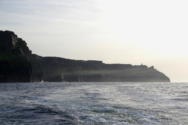 A line of mist in front of dark cliffs